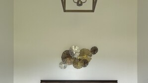 Ein ordentlich bezogenes Bett mit weißer Decke, einem Holzkopfstück und einer Nachttischlampe.