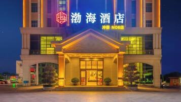 A hotel with a prominent entrance, a sign with Chinese characters, and a well-lit facade.