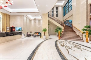 Un vestíbulo de hotel con mostrador de recepción, zona de estar y una escalera.