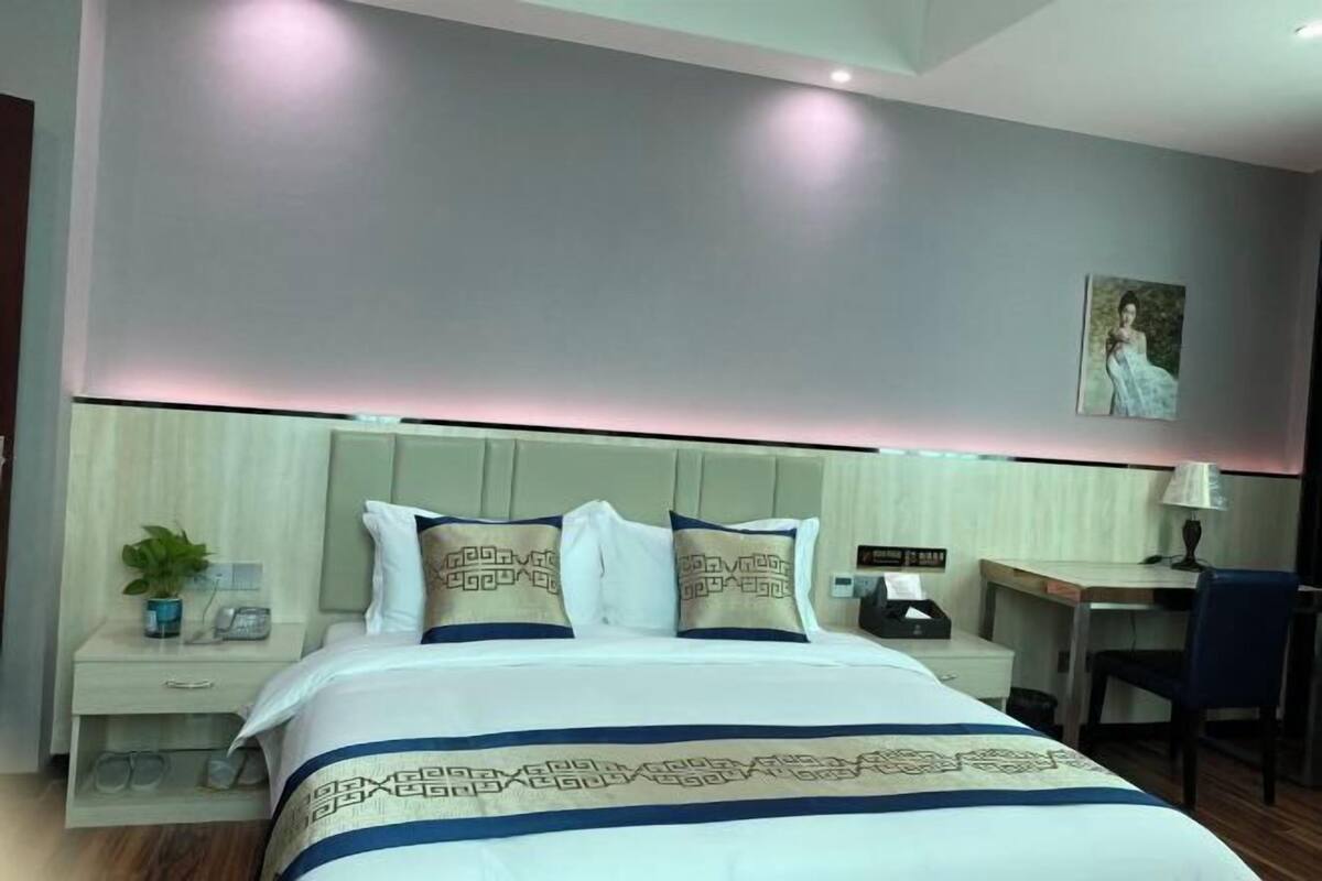 A modern hotel room with a neatly made bed, a desk, and a chair.