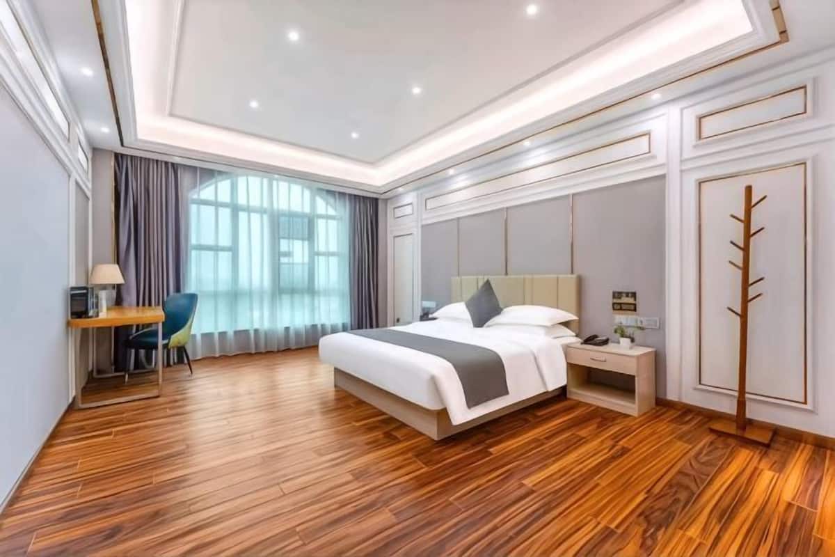 A modern hotel room with a large bed, bedside tables, a desk, and a chair.