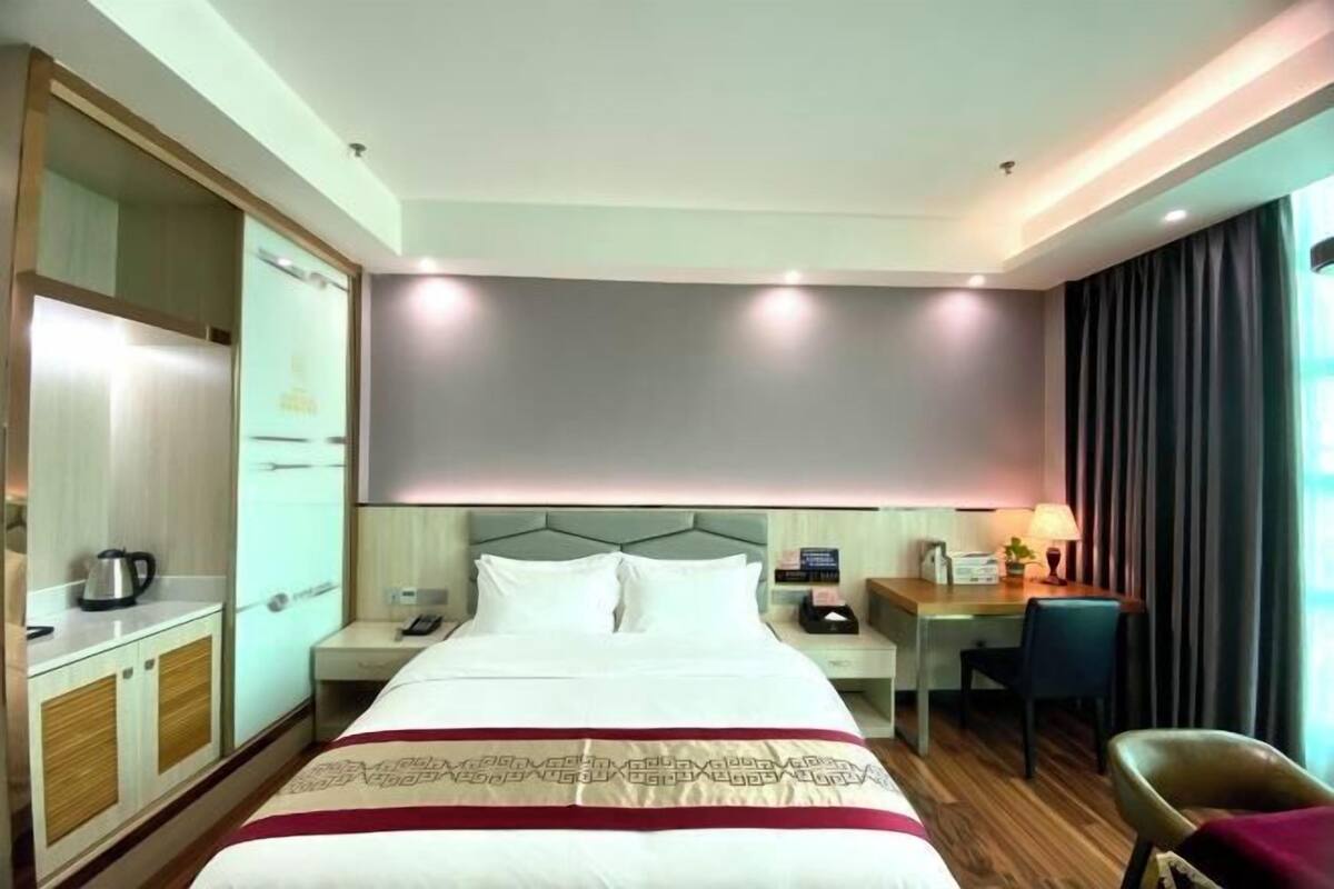 A hotel room with a large bed, bedside tables, a desk, and a chair.