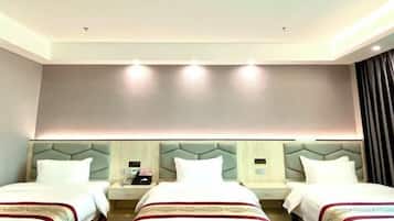 Una habitación de hotel con tres camas, cada una con cabecera y mesitas de noche.