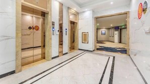 A modern hotel lobby with marble flooring, elevators, and a carpeted area. - Bohai Hotel （Taishan Chonglou) (Taishan)