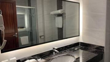 Un baño moderno con un espejo grande, un lavabo y un perchero para toallas.