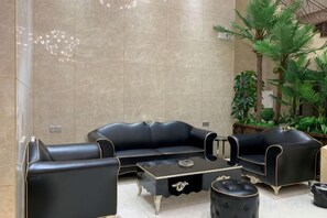 Un salón moderno con un sofá de cuero negro, una mesita de centro y un reposapiés a juego.