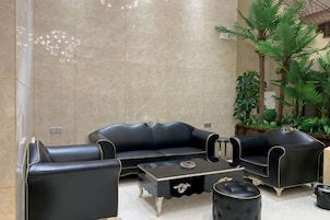 Un salón moderno con un sofá de cuero negro, una mesita de centro y un reposapiés a juego.