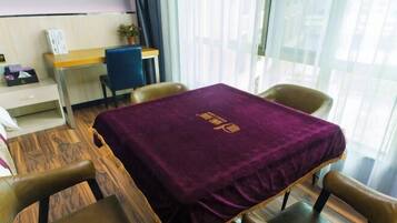 Una habitación con piso de madera, un escritorio con computadora, una silla y una mesa cubierta con un mantel morado.