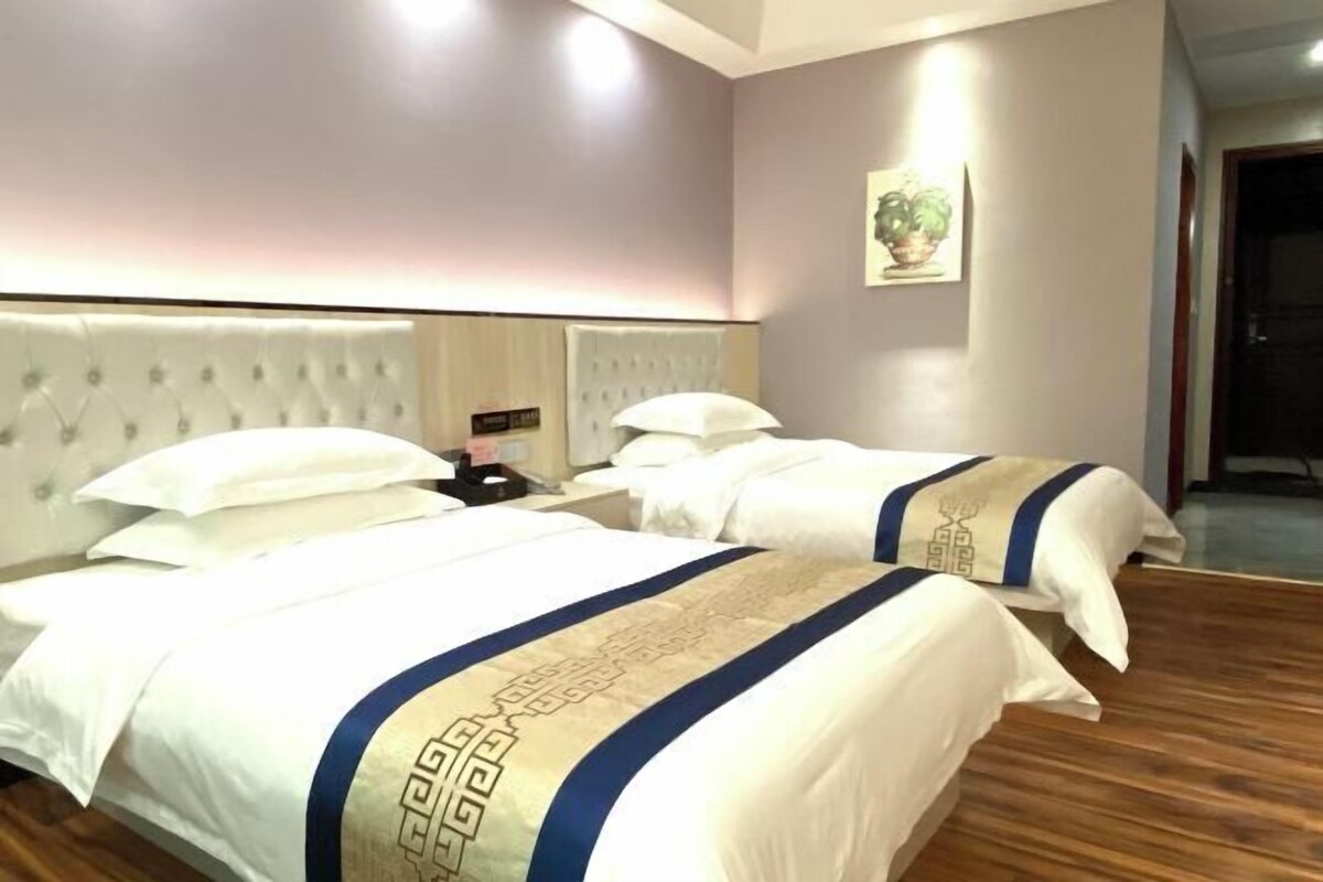 A hotel room with two beds, a tufted headboard, a bedside table, and a nightstand.