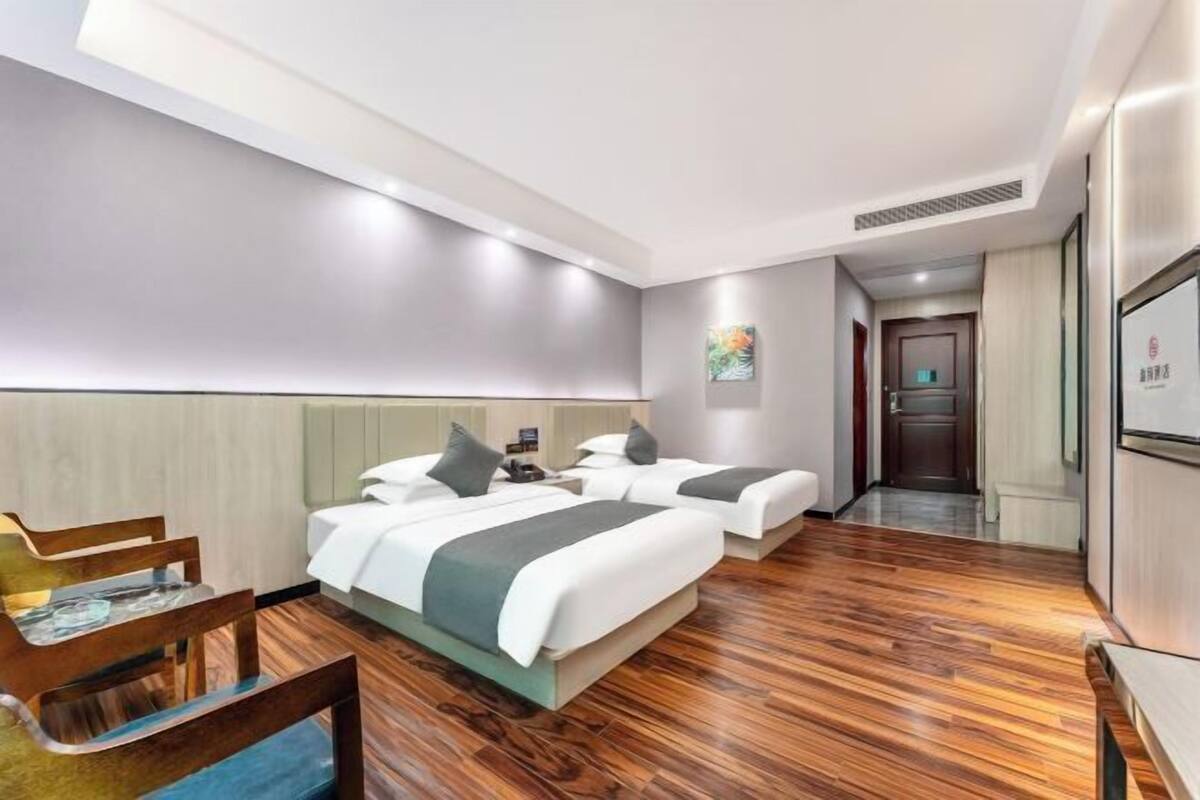 A hotel room with two beds, a desk, and a chair.