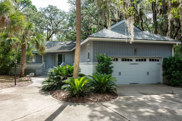 A two-story house with a garage, surrounded by mature trees and a well-maintained garden.