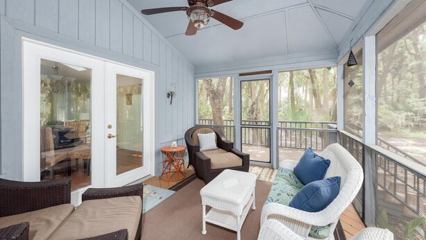 A covered porch with wicker furniture, a ceiling fan, and large windows overlooking a wooded area. - 3 BR/2BA Home! Screen Porch! Amenity access included! (Seabrook Island)