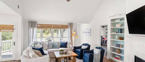 Een woonkamer met een bank, stoelen, een salontafel en een open haard.