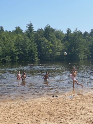 A beach with people swimming and playing in the water, surrounded by trees. - Lake Harmony/Split Rock Retreat -  Family Friendly - 2 Living Spaces (Lake Harmony)