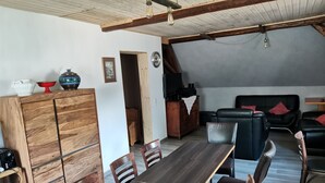 Een eetgedeelte met een houten tafel en stoelen, een kast en een bank.
