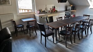 Een kleine keuken met een eethoek, met een groot raam, een ingebouwde magnetron en een compacte koelkast.