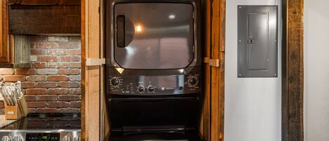 A compact kitchen with a built-in oven and stove, wooden cabinets, and a brick wall.