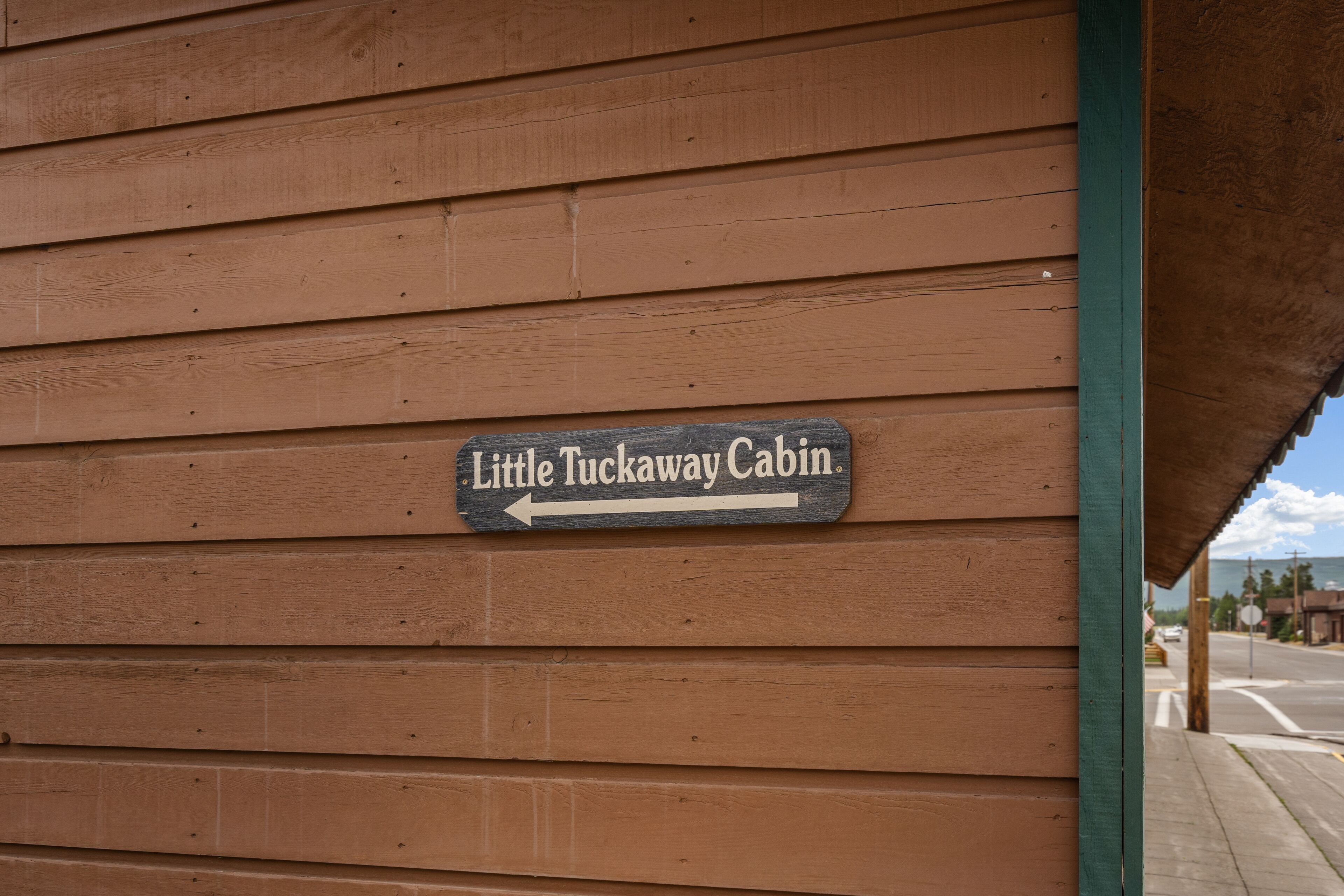 A wooden cabin with a sign indicating 'Little Tuckaway Cabin' and an arrow pointing to the left.