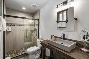A modern bathroom with a glass-enclosed shower, a wooden vanity with a sink, and a mirror. - Little Tuckaway (West Yellowstone)