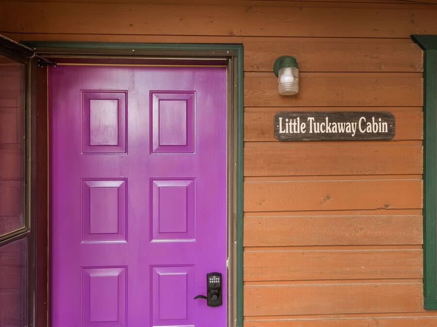 Een paarse deur met een cijferslot en een bordje met de tekst 'Little Tuckaway Cabin'.