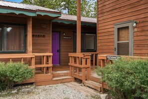 A wooden cabin with a purple door labeled "Little Tuckaway Cabin." - Little Tuckaway (West Yellowstone)