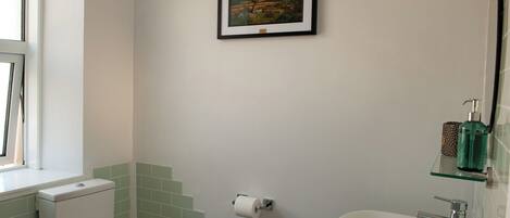 A bathroom with a toilet, sink, and framed picture on the wall.