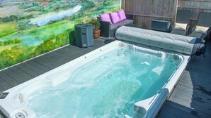 Ein Whirlpool auf einer Holzterrasse mit Blick auf eine grüne Landschaft.