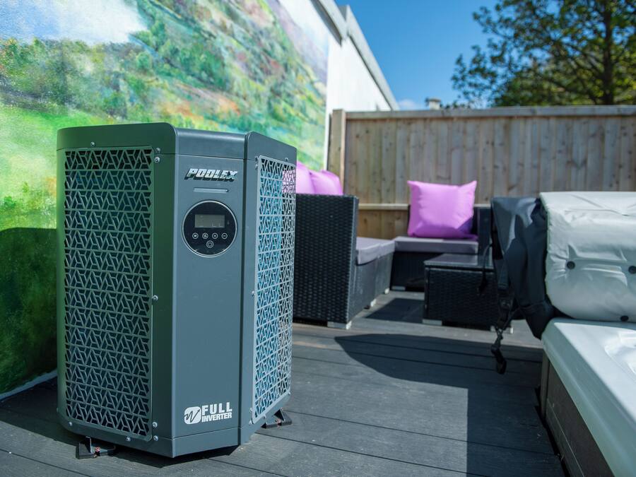 Un climatiseur portatif sur une terrasse, avec une clôture en bois et du mobilier d’extérieur en arrière-plan.