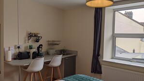 Eine kleine Küche mit Kaffeemaschine, Spüle und einem Fenster mit Blick auf Gebäude.