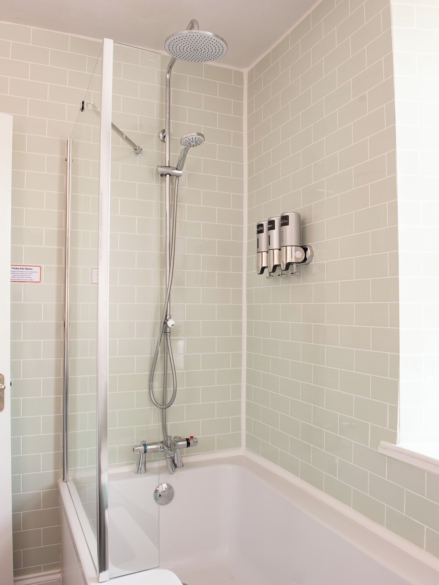 Une salle de bain moderne avec une douche à parois de verre, une baignoire blanche et un mur recouvert de carreaux.