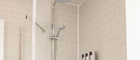 Une salle de bain moderne avec une douche à parois de verre, une baignoire blanche et un mur recouvert de carreaux.