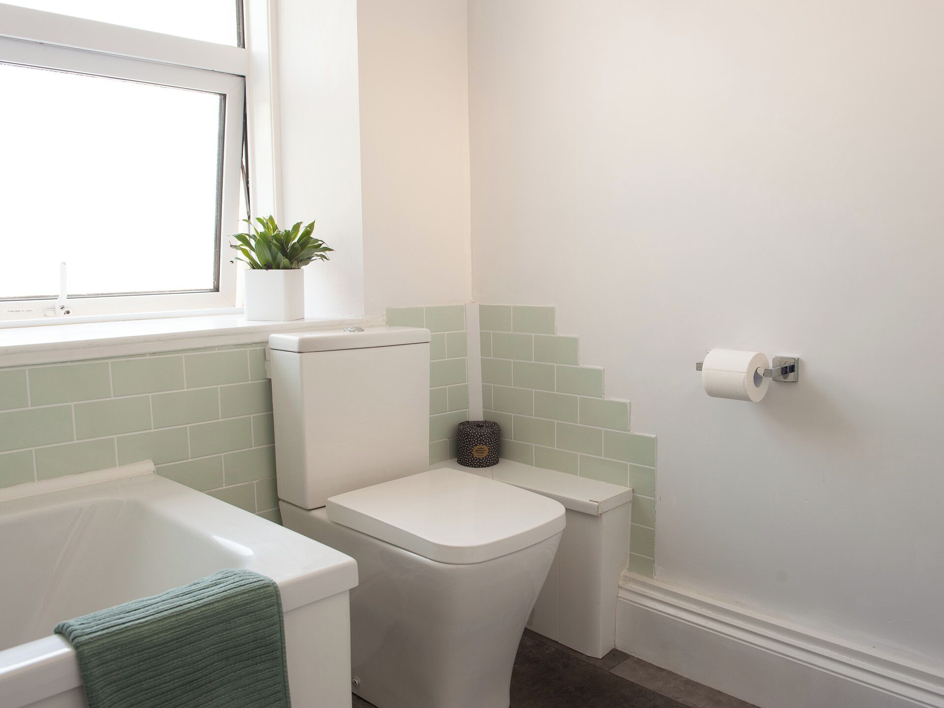A bathroom with a toilet, a bathtub, and a window.