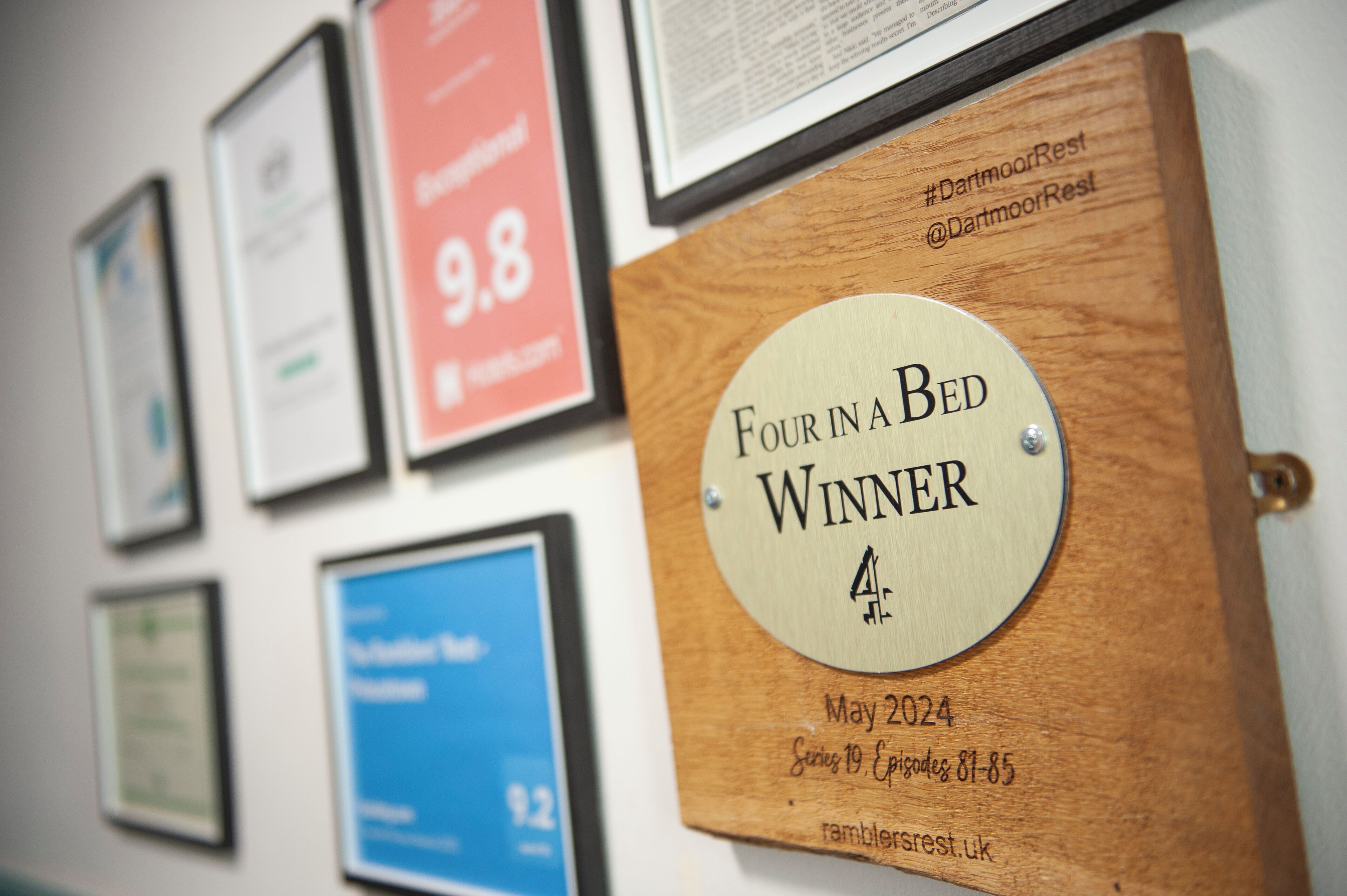 Une plaque en bois portant l’inscription « Gagnant de l’émission Four in a Bed » et la date « mai 2024 » est fixée à un mur.