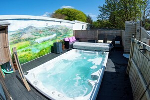 Un área de hidromasaje con un mural, terraza de madera y asientos.