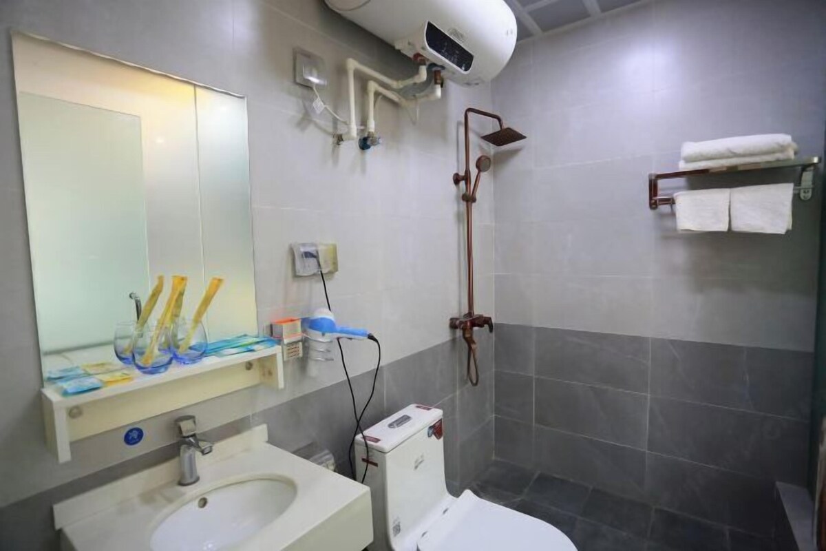 A bathroom with a sink, toilet, mirror, and shower.