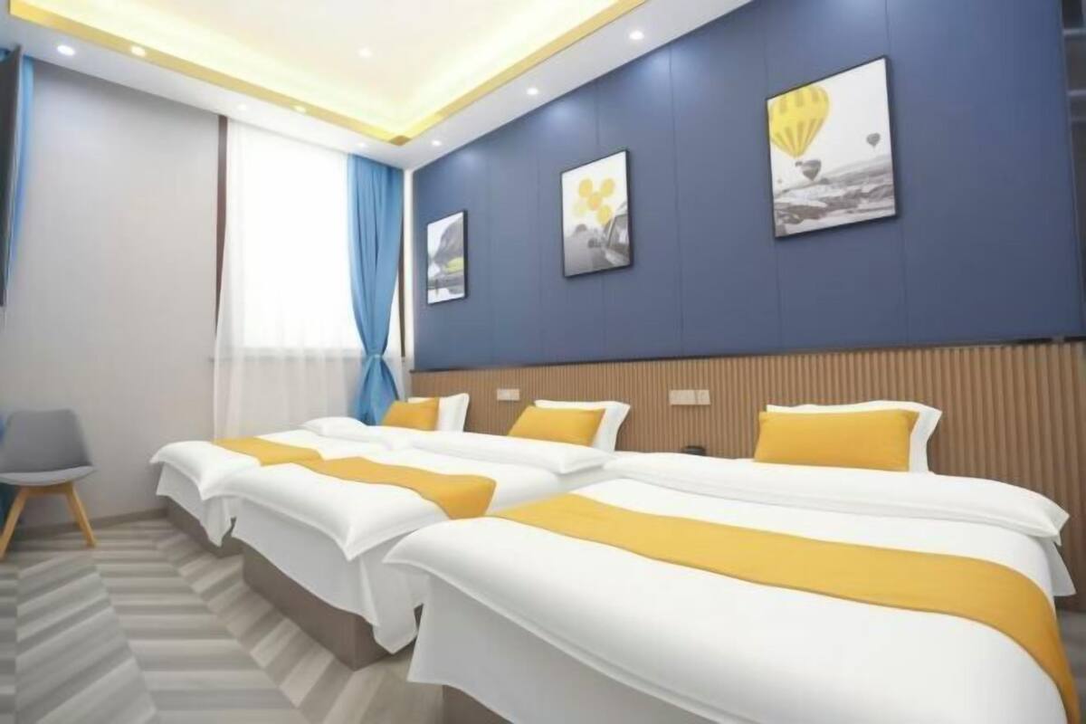 Ett hotellrum med två sängar, en stol och ett fönster med gardiner.