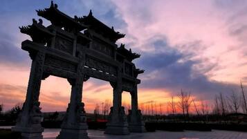 A traditional gate structure with intricate carvings, set against a twilight sky.