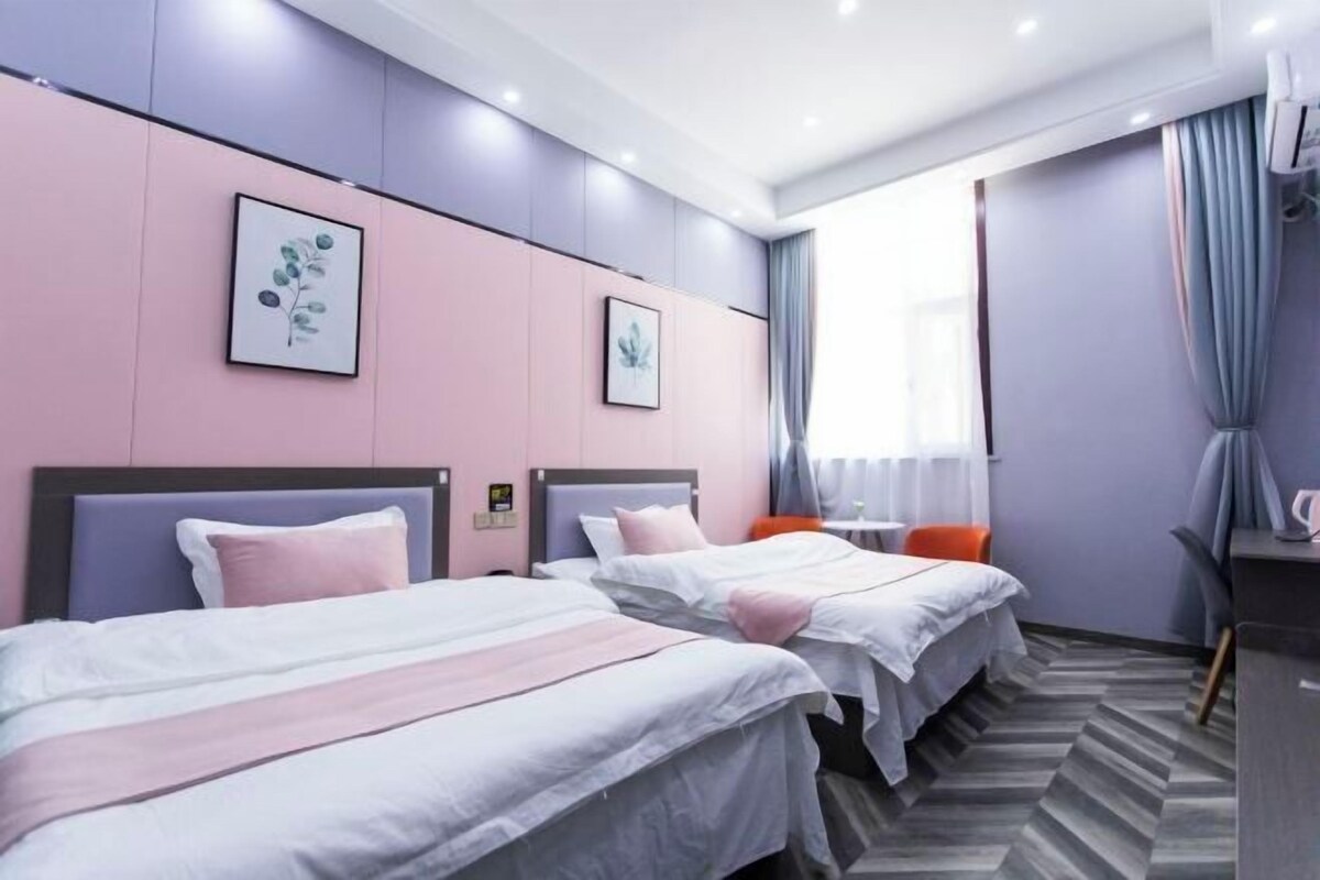 A hotel room with two beds, a desk, and a chair.