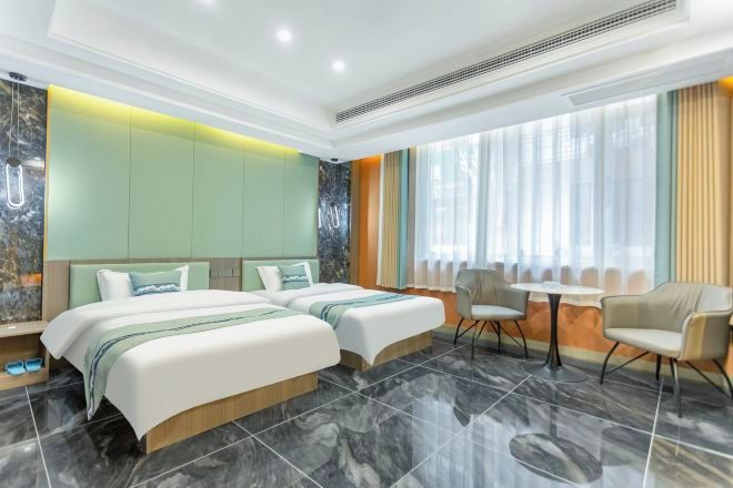 A modern hotel room with two beds, a small table, and chairs.