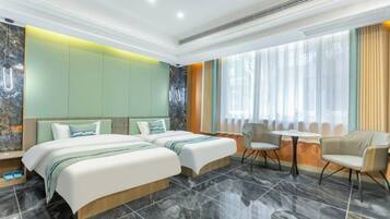 A modern hotel room with two beds, a small table, and chairs.