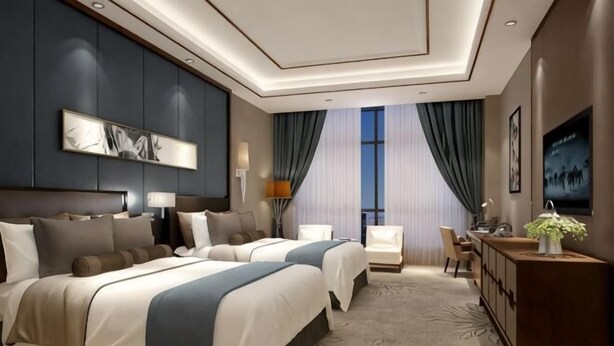 Ein Hotelzimmer mit zwei Betten, einem Schreibtisch, einem Stuhl, einem Fernseher und einem großen Fenster mit Vorhängen.