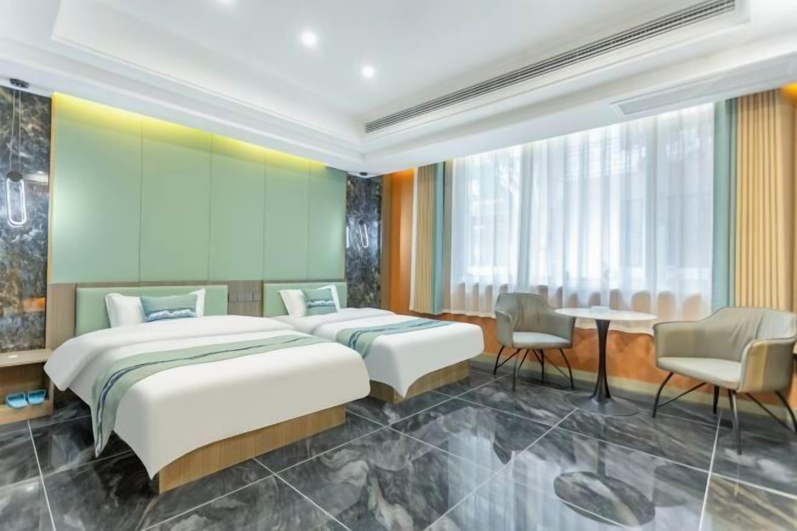 A hotel room with two beds, a small table, and chairs.