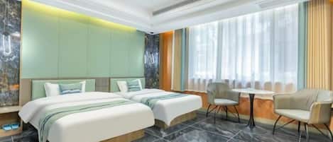 A hotel room with two beds, a small table, and chairs.