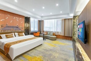 A hotel room with a large bed, a sofa, a small table, and a TV.