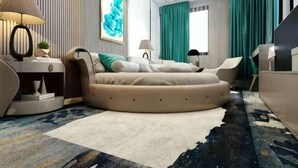 Ein modernes Schlafzimmer mit einem runden Bett, einem Schreibtisch, einem Sessel und einem Fernseher.
