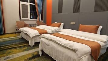 Une chambre d’hôtel avec deux lits, une fenêtre avec des rideaux, une petite table et une chaise.