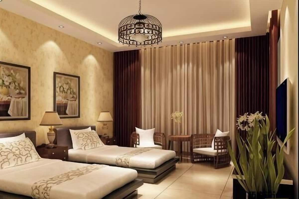 A hotel room with two beds, a chandelier, artwork on the walls, a TV, and a large window with curtains.