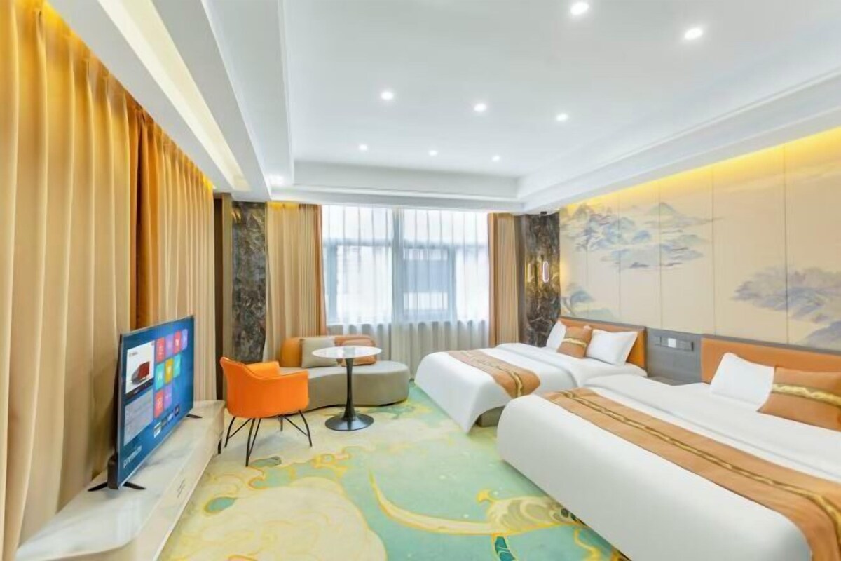 A hotel room with a bed, a sofa, a small table, and a TV.