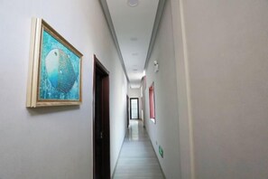 Un corridoio con un quadro appeso a sinistra, una porta a destra e un lungo ingresso che porta a una stanza.