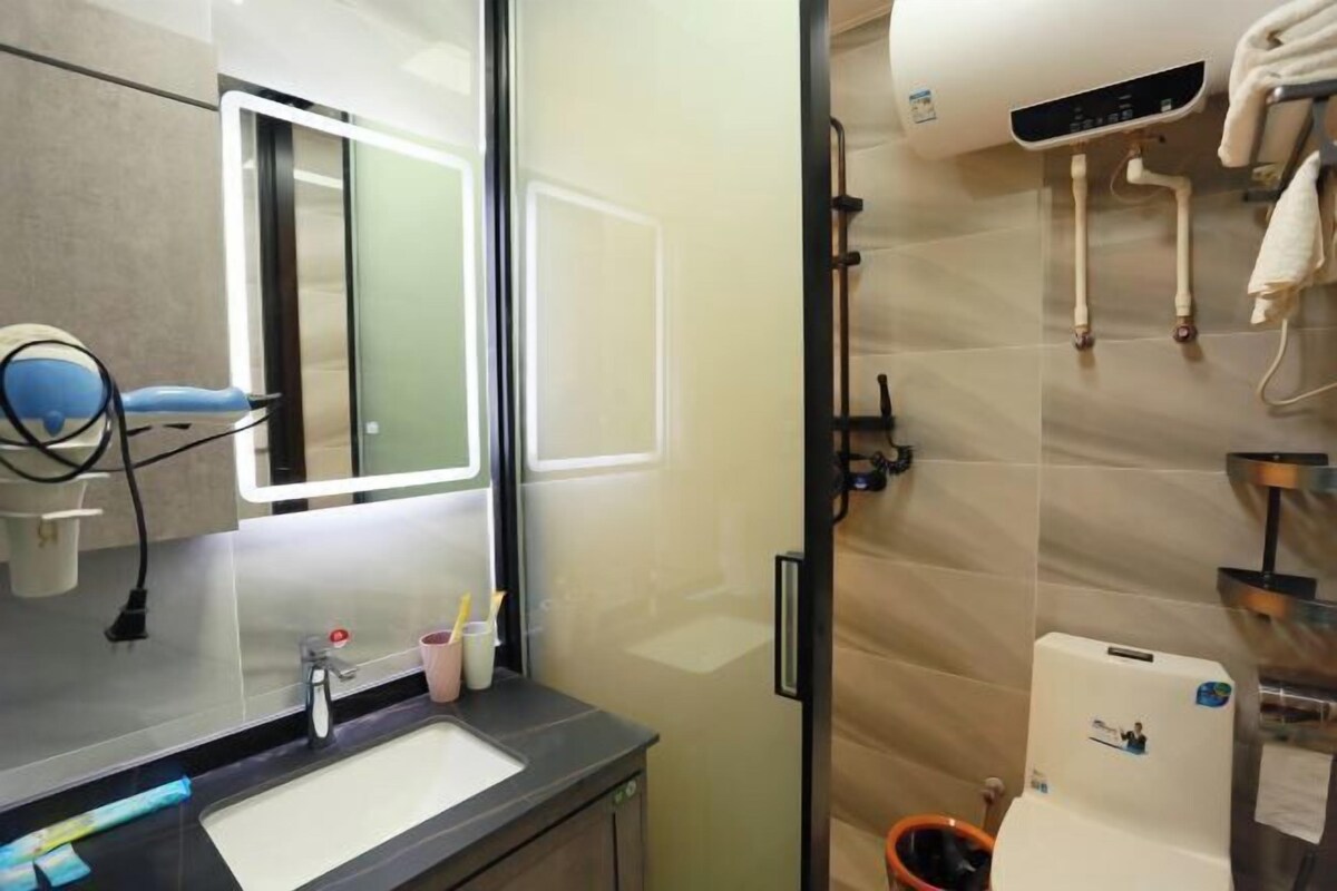A modern bathroom with a large mirror, a sink, and a shower area.